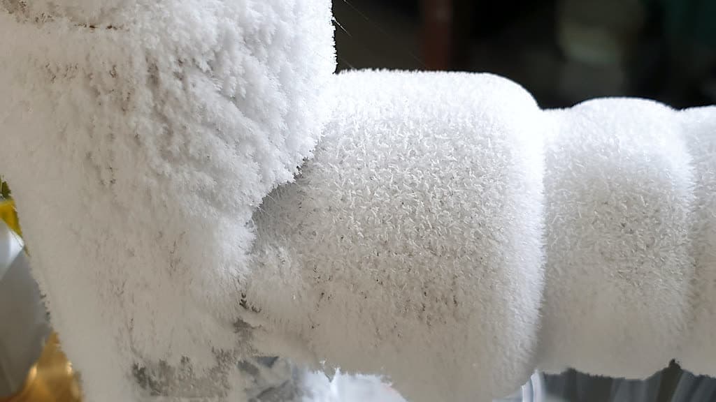 Thick white frost covering a pipe joint