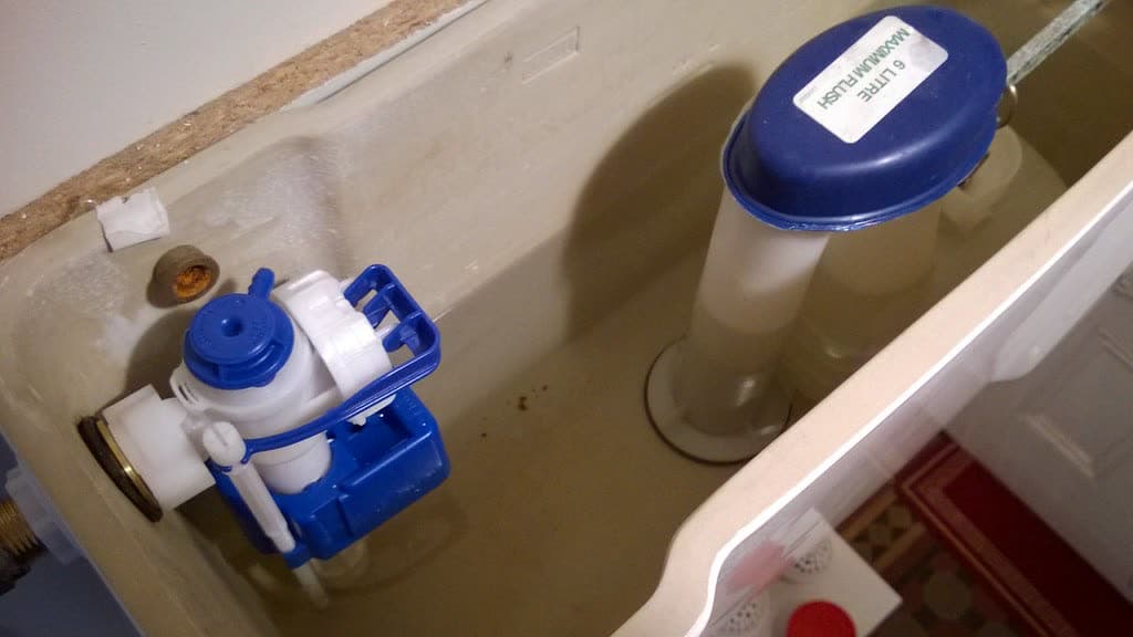 Inside a toilet tank showing the fill valve and flush valve