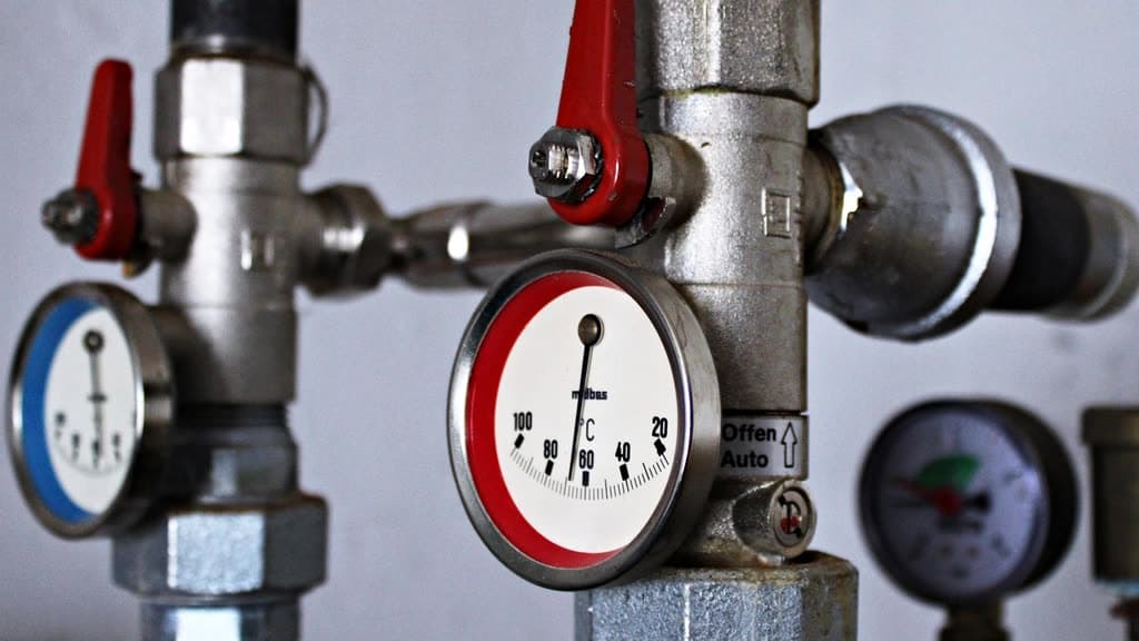 Temperature gauges and red shutoff valves on heating system pipes