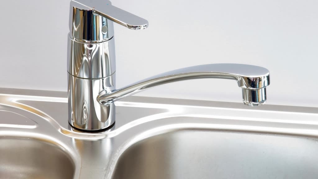 Chrome single-handle faucet over a stainless steel kitchen sink